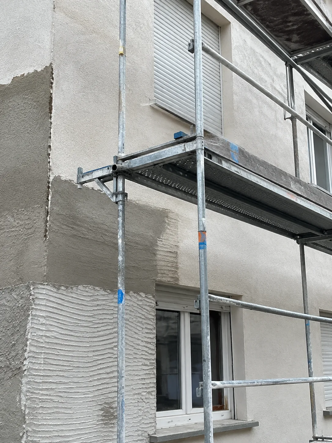 Fassadenflächen mit vorbereiteten Putzbereichen und einem Baugerüst.
