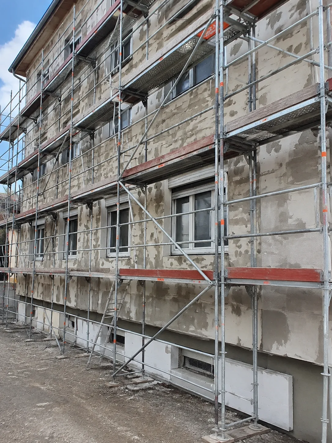 Bestandsgebäude mit Gerüst und vorbereiteten Fassadenflächen während der Sanierung.